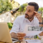Portrait of Smart Casual Businessman Going Over Paperwork While Sitting in Outdoor Cafe