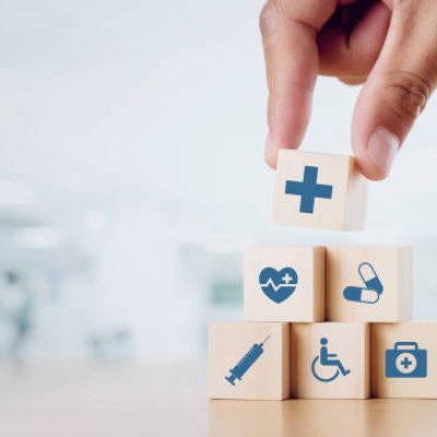 Close up man hand arranging wood block with healthcare medical icon on hospital background. Health care and Health insurance concept.