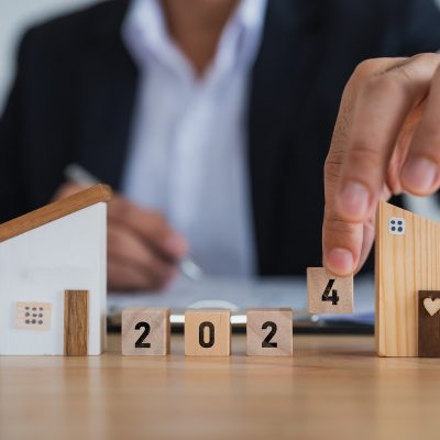 2024 new year target home loan trends. Businessman hold model house and wood blocks word LOAN. plan finances investments and savings to buy house real estate. Home accounting and tax and insurance.